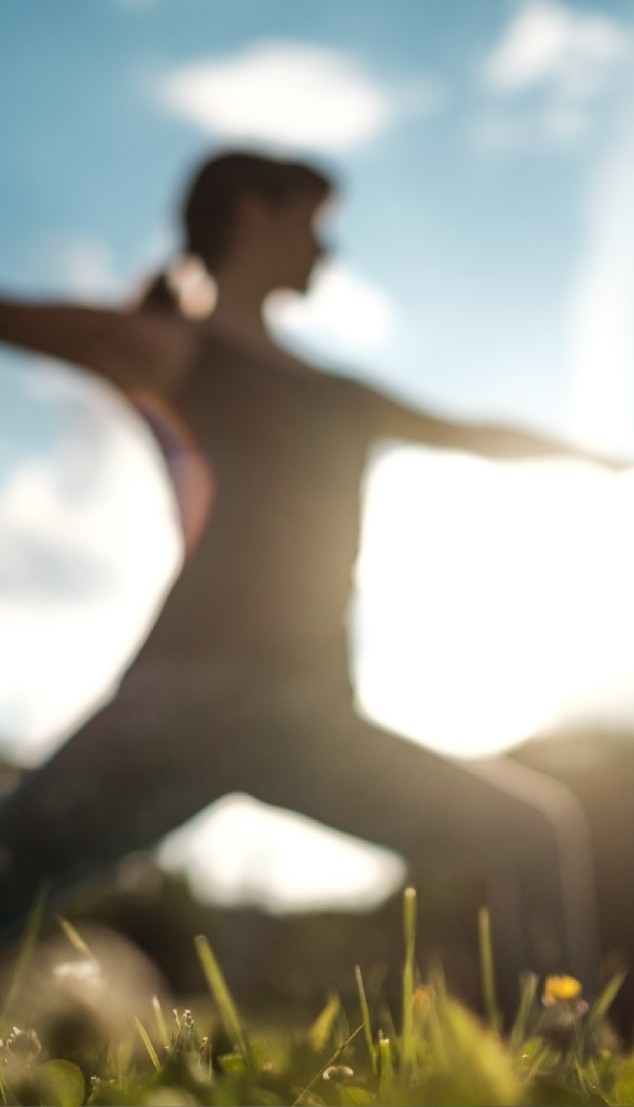 A person stretching outdoors against a bright sky